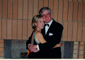 A photo of Charles Koch, dressed in a tuxedo for a formal event, embracing wife Liz Koch wearing a black dress.